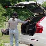 Woman placing black bag in the trunk of white car while holding a baby seat in her other hand. "Perfect for on-the-go" - product thumbnail