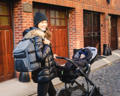 Woman carrying the diaper bag backpack while pushing a stroller - product thumbnail