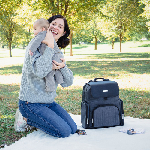 Woman holding baby next to the best diaper backpack  - product thumbnail