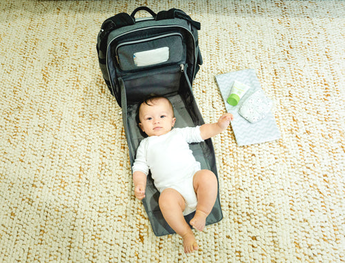 Baby laying on the built in changing station in the diaper bag backpack - product thumbnail