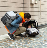 A man carrying the diaper bag backpack and checking on a baby - product thumbnail