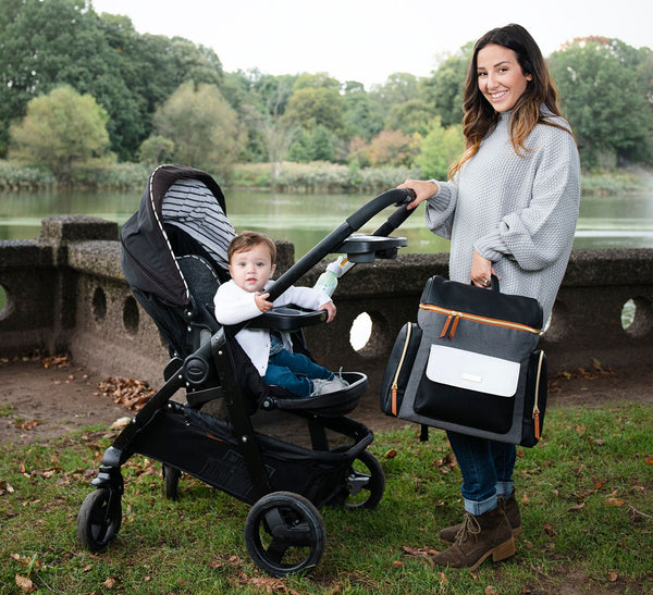 Woman holding grey and black diaper bag and pushing stroller - product thumbnail