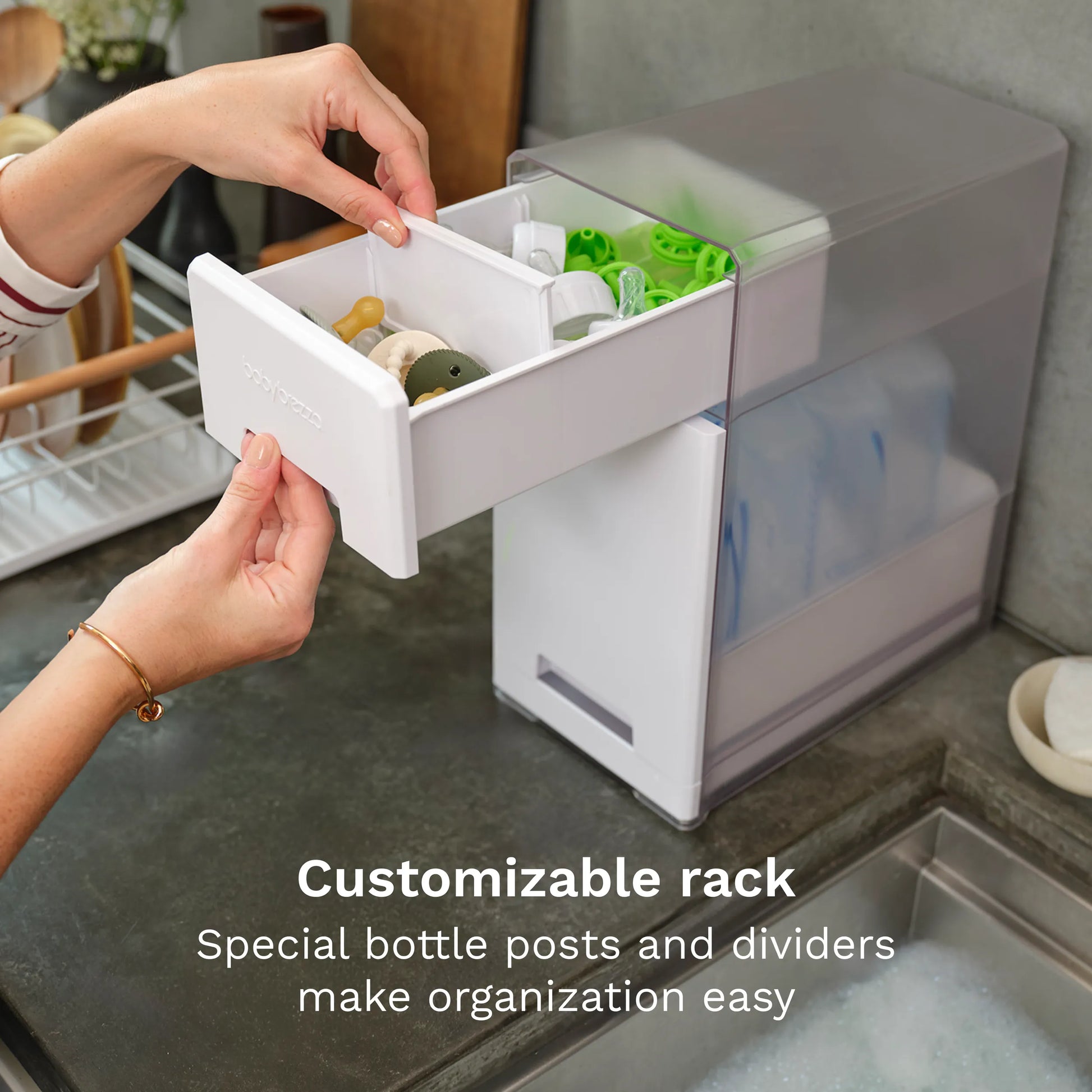 Person using a customizable bottle rack with bottle posts and dividers on a kitchen counter.