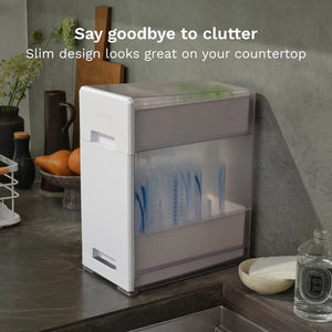 White Baby Brezza bottle drying rack on a countertop with text 'Say goodbye to clutter, Slim design looks great on your countertop'.