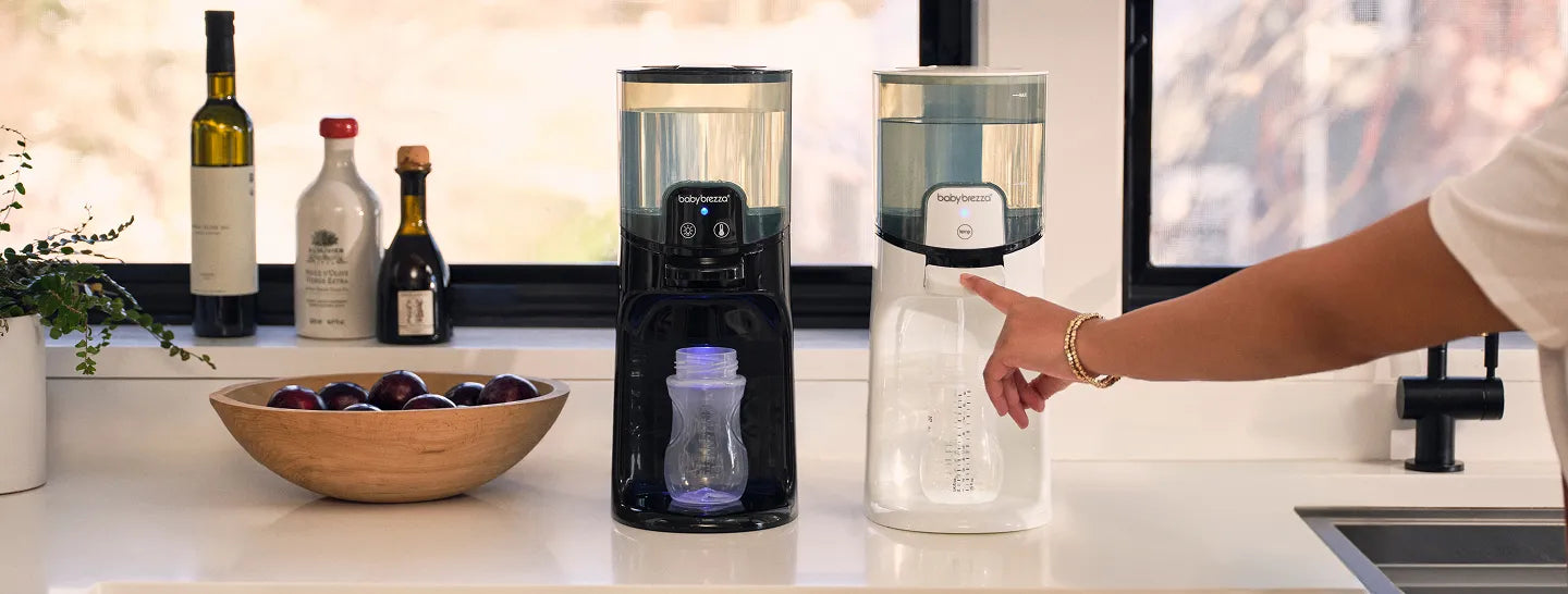 Two warm water dispensers on a kitchen counter with a hand reaching towards one of them.