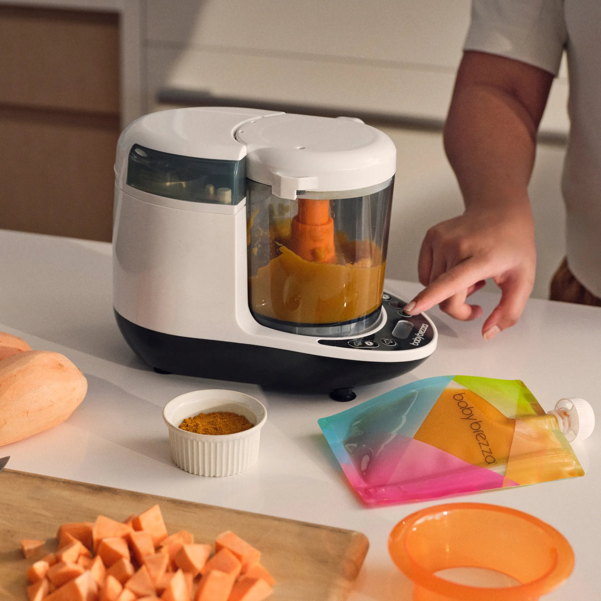 mom using baby brezza one step food maker deluxe to steam and blend sweet potatoes