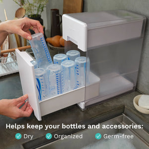 Baby Brezza Bottle drying rack with bottles on a kitchen counter, text indicating "Helps keep your bottles and accessories dry, organized, germ-free"