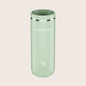 green baby brezza superfast portable travel bottle warmer with digital display on a beige background