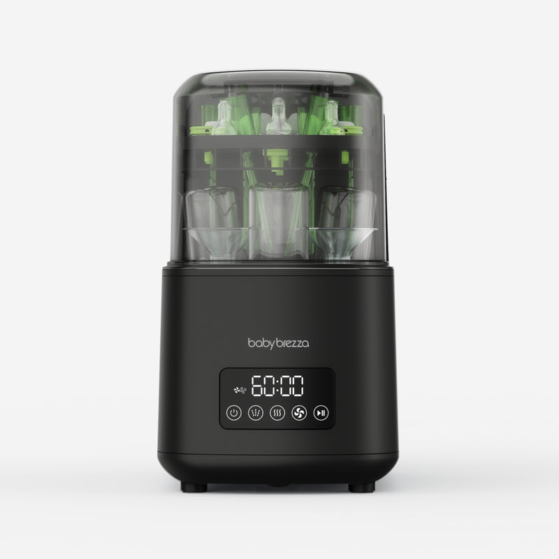 A Baby Brezza baby bottle washer shown on a light gray background. The device has a matte black base with a digital display showing '60:00' and is topped with a clear plastic chamber containing green and clear baby bottles.