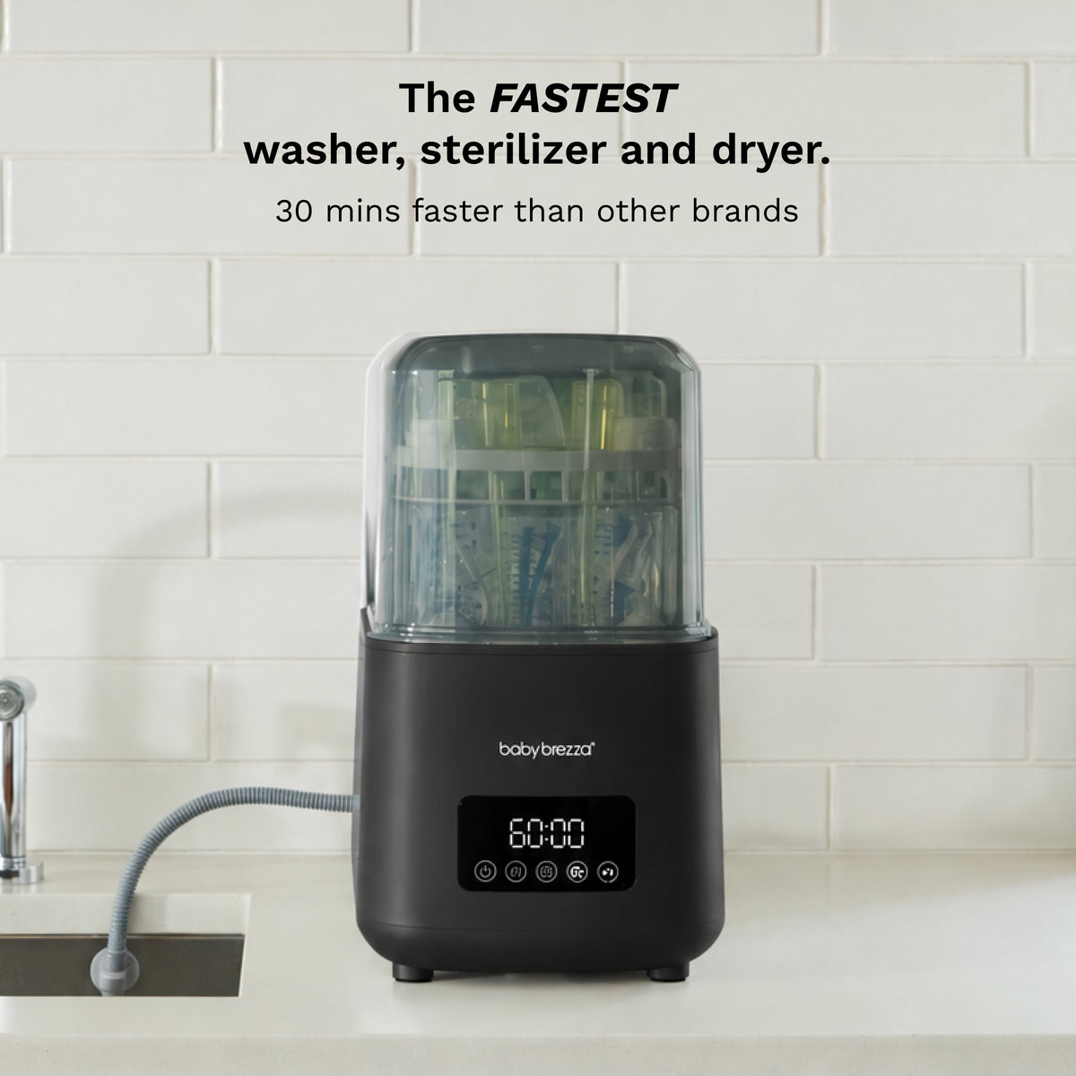 A countertop body brezza instant washer, sterilizer and dryer machine in black with a clear top, set against a white subway tile wall. Text at the top reads 'The FASTEST washer, sterilizer and dryer.