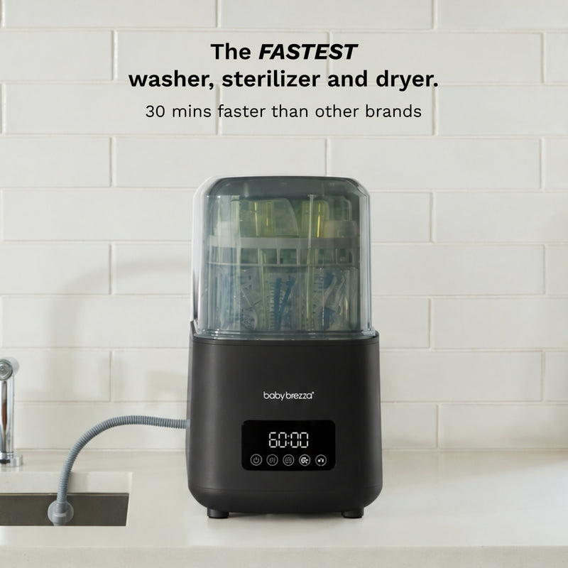 A countertop body brezza instant washer, sterilizer and dryer machine in black with a clear top, set against a white subway tile wall. Text at the top reads 'The FASTEST washer, sterilizer and dryer.