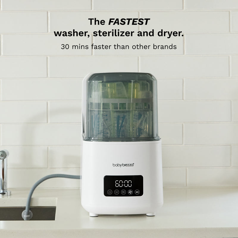 A white Baby Brezza multi-function baby sterilizer, dryer, and washer sits on a kitchen counter with a tiled backsplash. Text at the top reads 'The FASTEST washer, sterilizer and dryer.