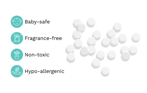 White round tablets scattered on a white background with four teal icons and text listing product benefits: Baby-safe, Fragrance-free, Non-toxic, and Hypo-allergenic.