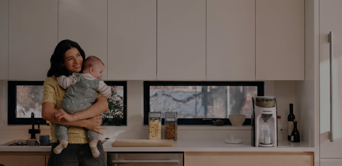 Parent holding a baby next to a Baby Brezza formula machine - Brezza Care membership program
