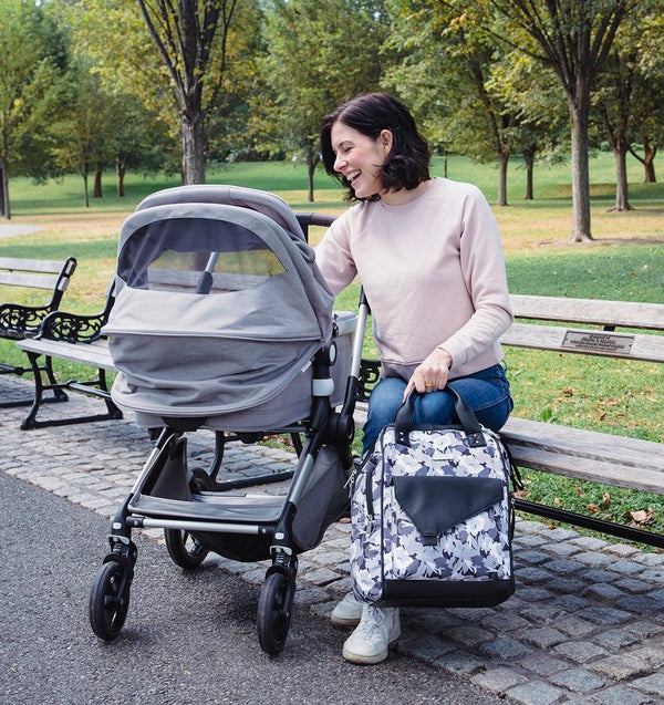 Woman sitting on a bench holding floral diaper bag  - product thumbnail