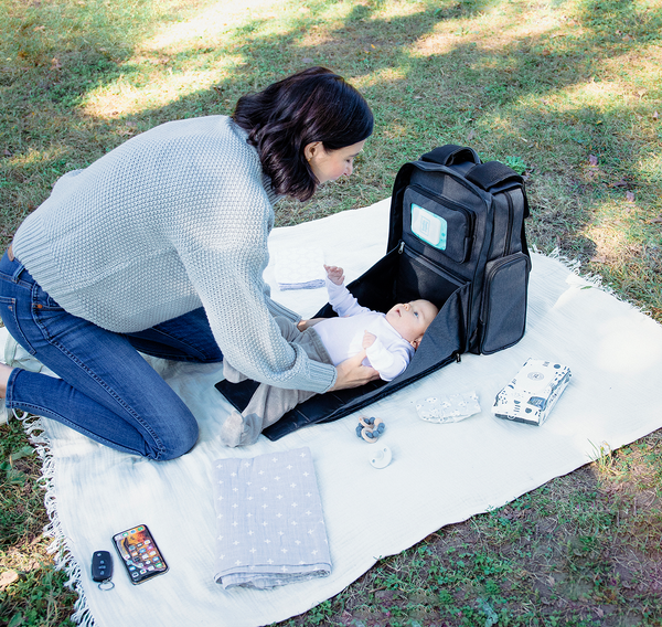 Woman changing baby with the diaper bag with attached changing pad - product thumbnail